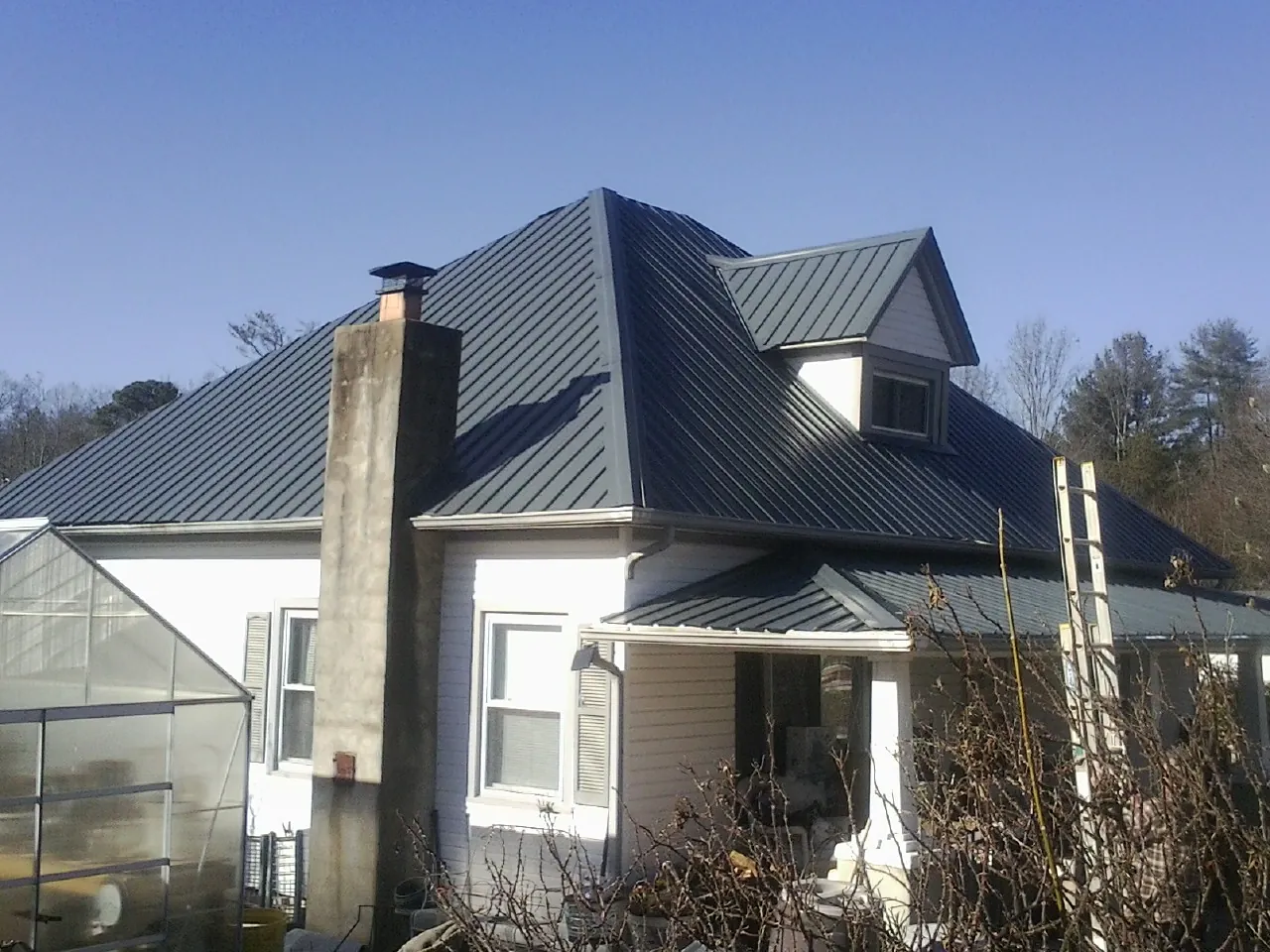 Dark blue standing seam metal roof on a white farmhouse with dormer — Slate & Tile Roof Repair by Roofing Brothers in Callicoon