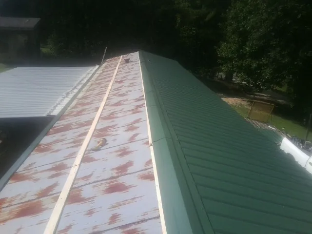 Old rusted panels beside newly installed green metal roofing — Wind Damage Roof Repair by Roofing Brothers in Callicoon