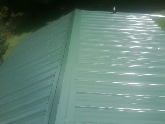 New green metal panels meeting at the ridge of a roof — Flat Roof Repair work by our crew in Callicoon