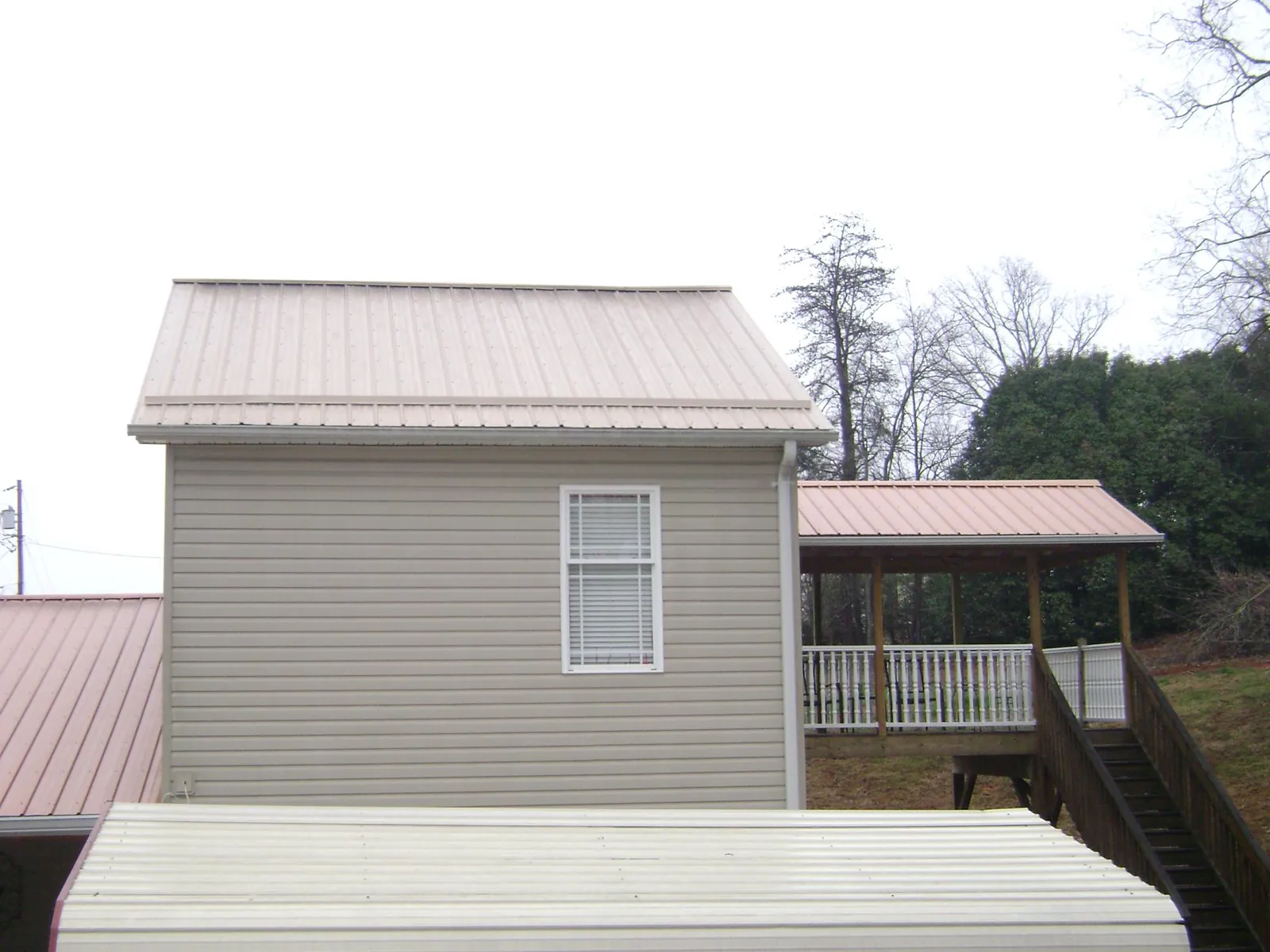 Tan metal roofs on a two story addition and attached porch, from a Roof Replacement job in Callicoon