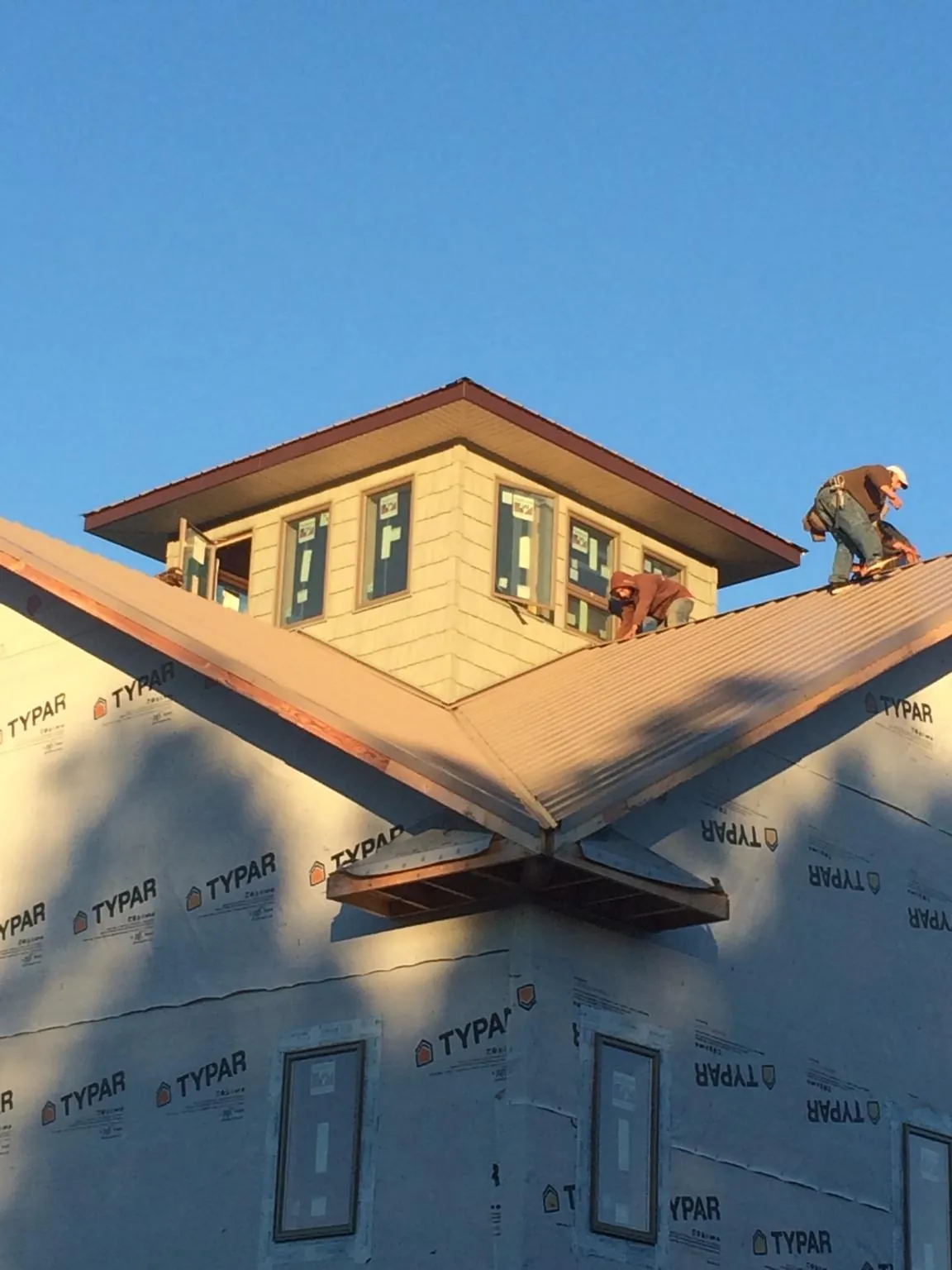 Roofers working around a rooftop cupola on a new metal roof at sunset — Roof Waterproofing in Callicoon by Roofing Brothers